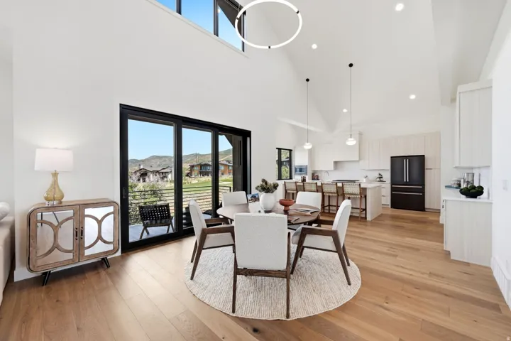 Vaulted ceilings, large sliding glass doors, upper transom windows, wood-finish flooring, and a contemporary kitchen with a center island