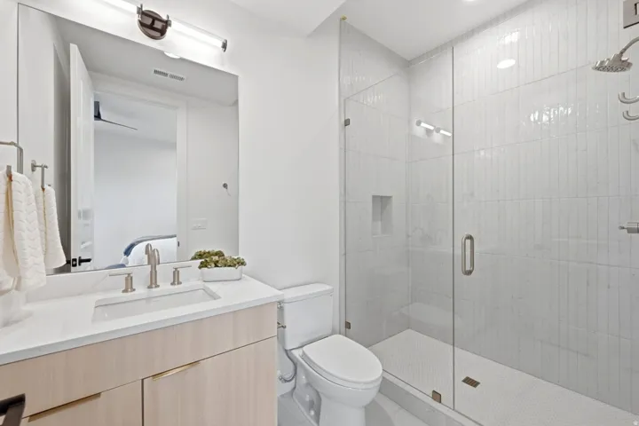 Modern bathroom featuring a glass-enclosed shower with vertical tile, a built-in shower niche, and a rain showerhead