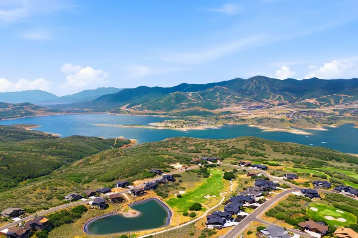 Expansive lake and mountain scenery, featuring a golf course, a large body of water, and residential properties