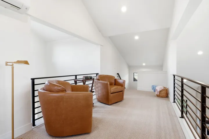 Open-concept loft with vaulted ceilings, recessed lighting, and a contemporary black metal railing