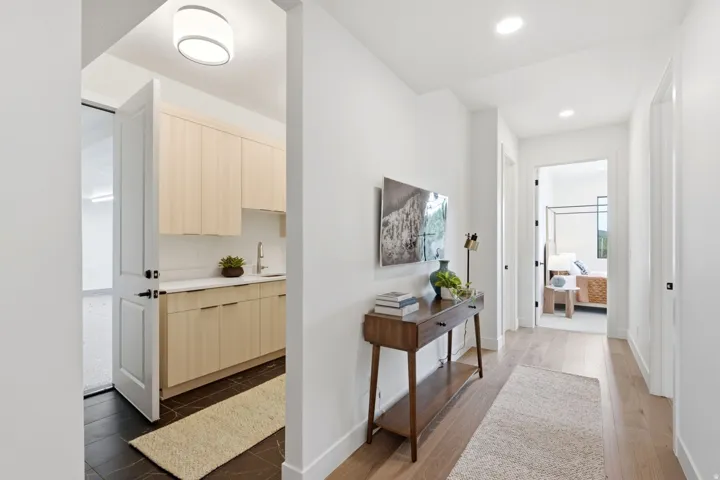 Recessed lighting throughout, wood-finish flooring, light-toned cabinetry, white countertops, and a utility sink