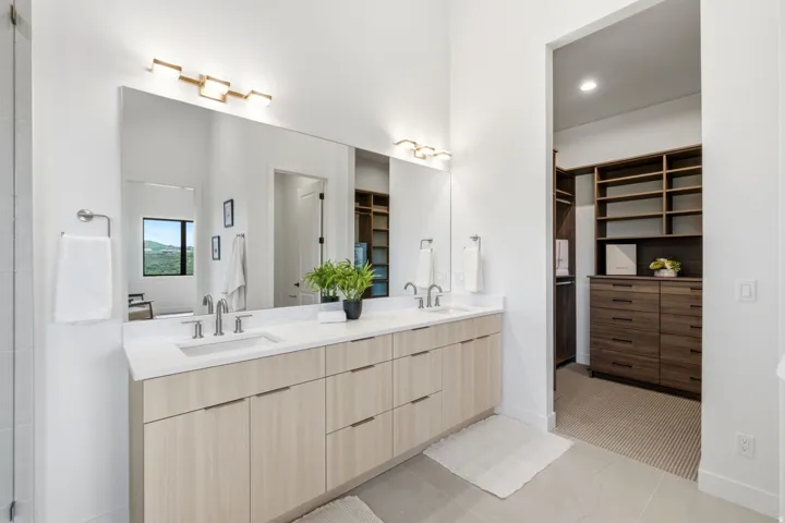 Dual vanity with light wood-finish cabinetry, integrated sinks, and polished chrome fixtures