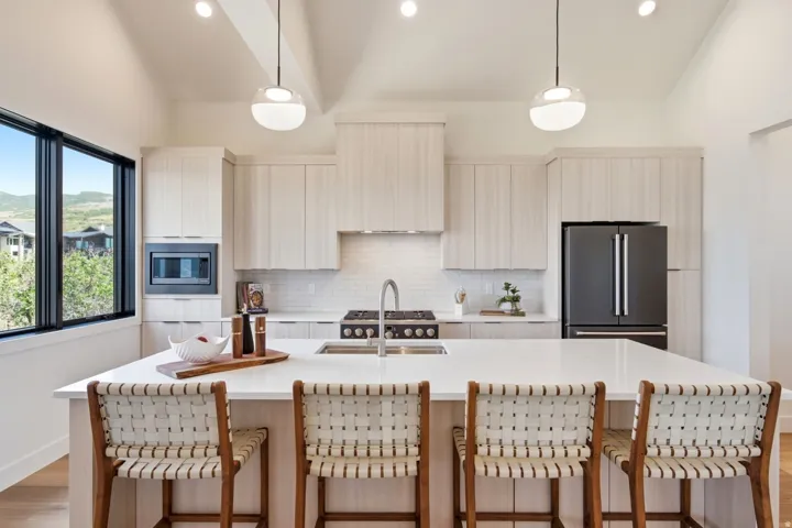 Kitchen featuring a large island with counter seating, light wood-finish cabinetry, a gas range, a built-in microwave, and a black French door refrigerator