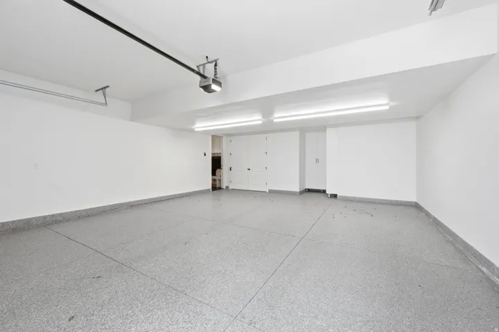 Garage featuring an epoxy coated floor, built-in storage cabinetry, and overhead lighting