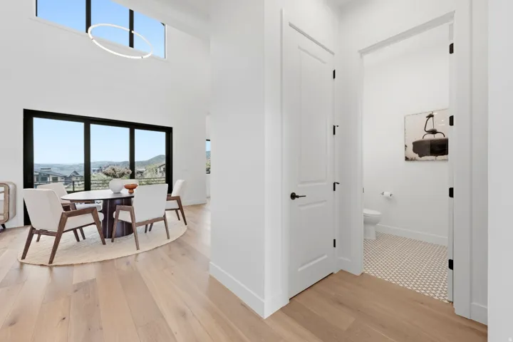 High ceilings with an upper window, large dark-framed windows, and light wood-finish flooring