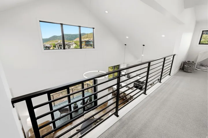 Loft area featuring a black horizontal bar railing, neutral-toned carpet, recessed lighting, and a large window