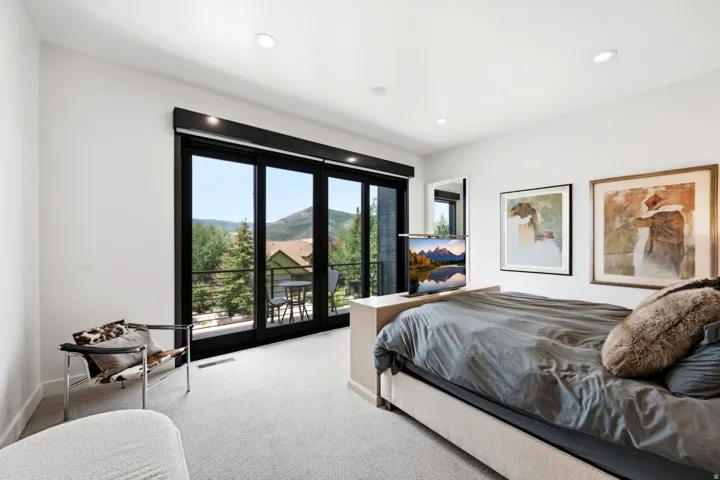 Recessed lighting illuminates the space, featuring a built-in media console at the foot of the bed
