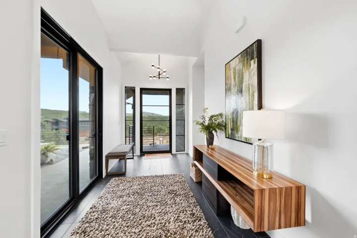 Vaulted ceilings with a contemporary chandelier, dark wood-finish flooring, and a floating wood-grain console