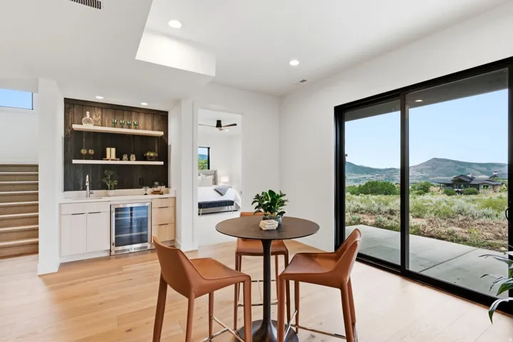 Built-in wet bar with wood-finish paneling, under-counter refrigeration, and open shelving