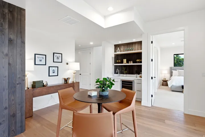 Light wood-finish flooring, built-in wet bar with shelving, integrated beverage cooler, and recessed lighting