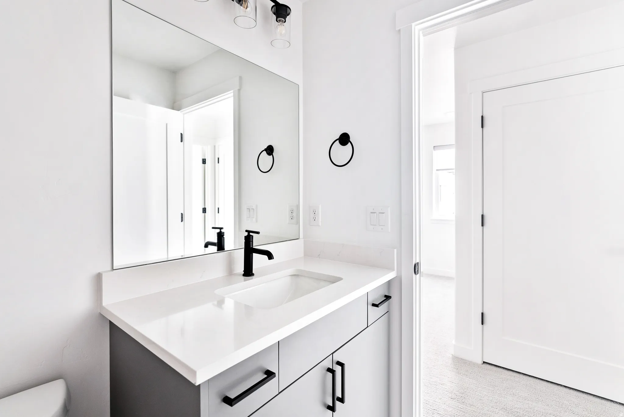 Vanity with a white countertop and integrated sink, matte black faucet, and gray cabinetry with black hardware