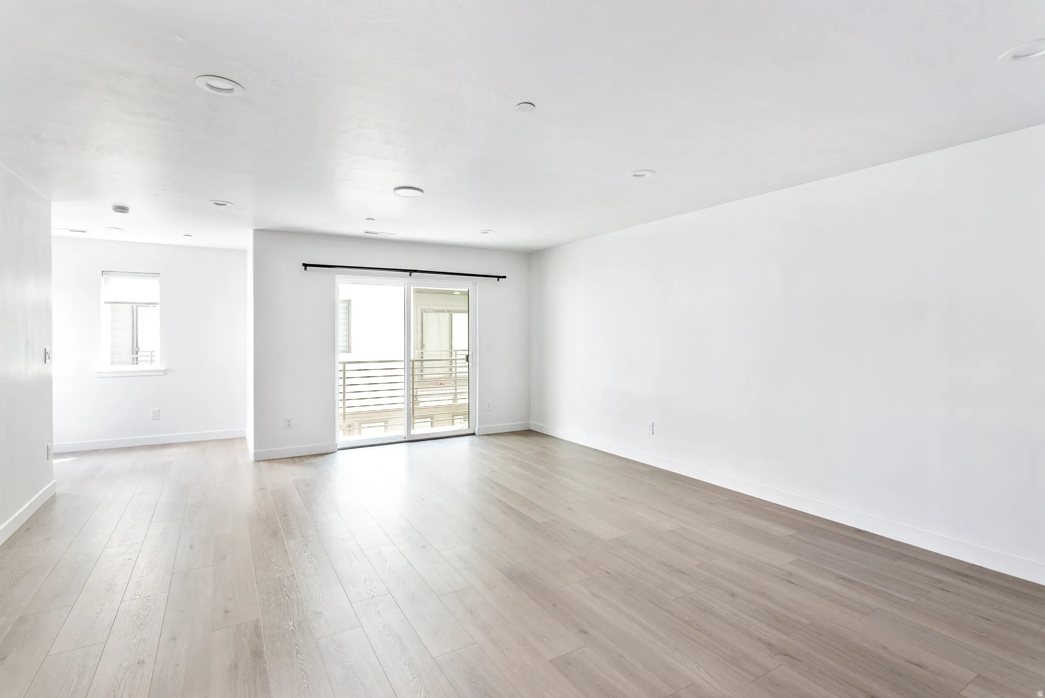 Wood-finish flooring throughout, recessed lighting, and a sliding glass door with balcony access