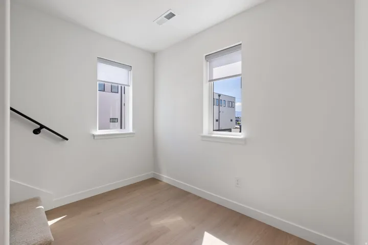 Wood-finish flooring, white walls, and two windows with roller shades