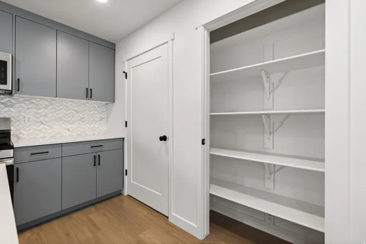 Modern cabinetry with matte gray finishes, white countertops, and a patterned tile backsplash