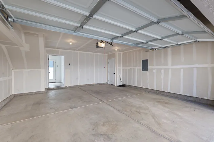 Two-car garage with concrete flooring, overhead lighting, and an automatic garage door opener