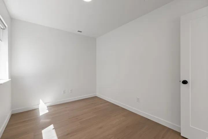 Recessed ceiling lighting, wood-finish flooring, white walls, and a white door with black hardware