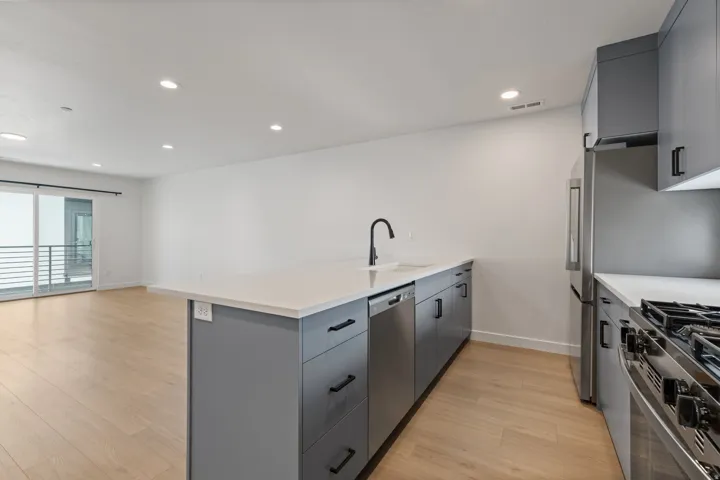 Open-concept living space featuring wood-finish flooring, recessed lighting, and a sliding glass door