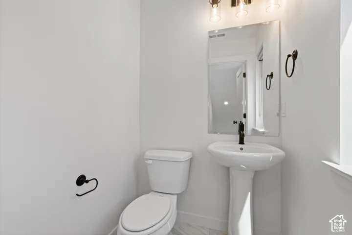 Pedestal sink with black-finish faucet, rectangular mirror, and three-light vanity fixture
