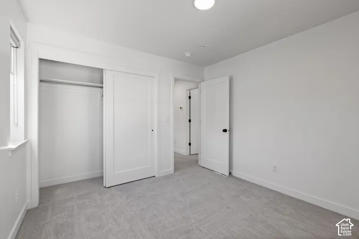 Neutral color palette, recessed lighting, white trim, sliding closet doors, and light-toned carpeting