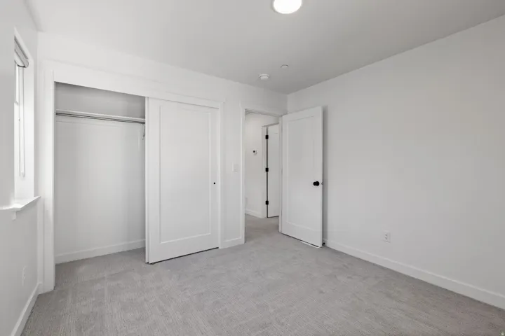 Neutral color palette, recessed lighting, white trim, sliding closet doors, and light-toned carpeting