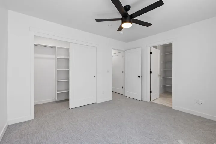 Recessed lighting, black ceiling fan, light gray carpeting, built-in closet shelving, and white interior doors