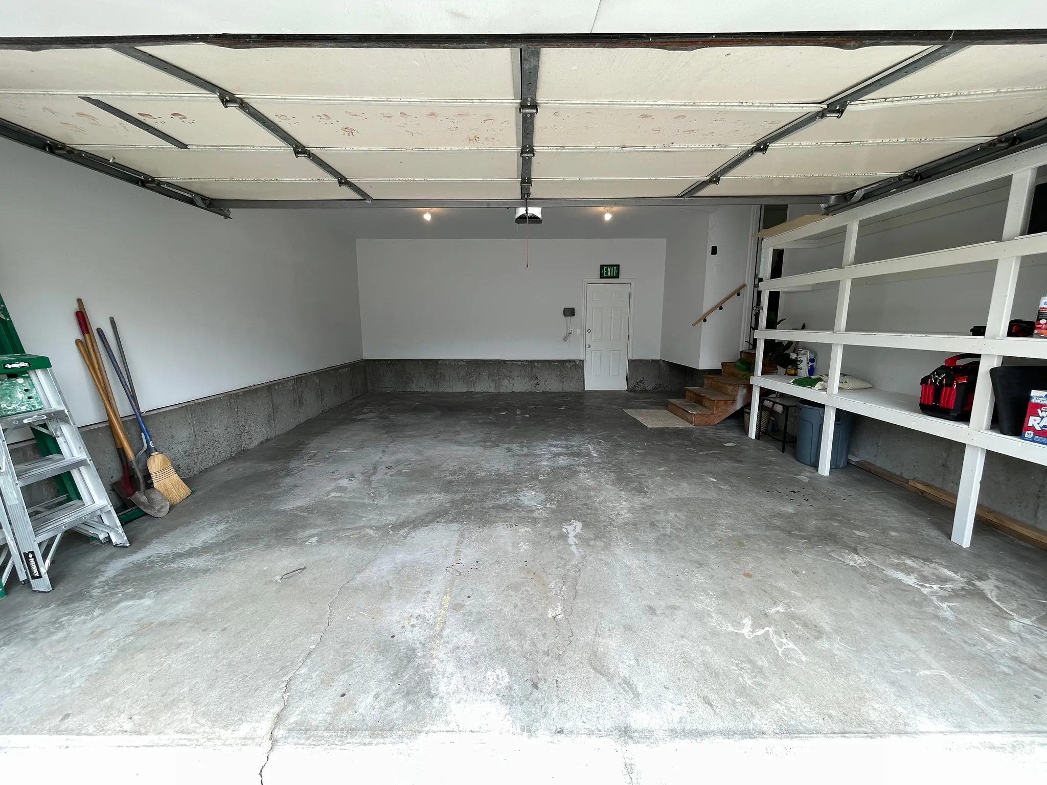 Attached garage with concrete flooring, built-in shelving, and interior access door