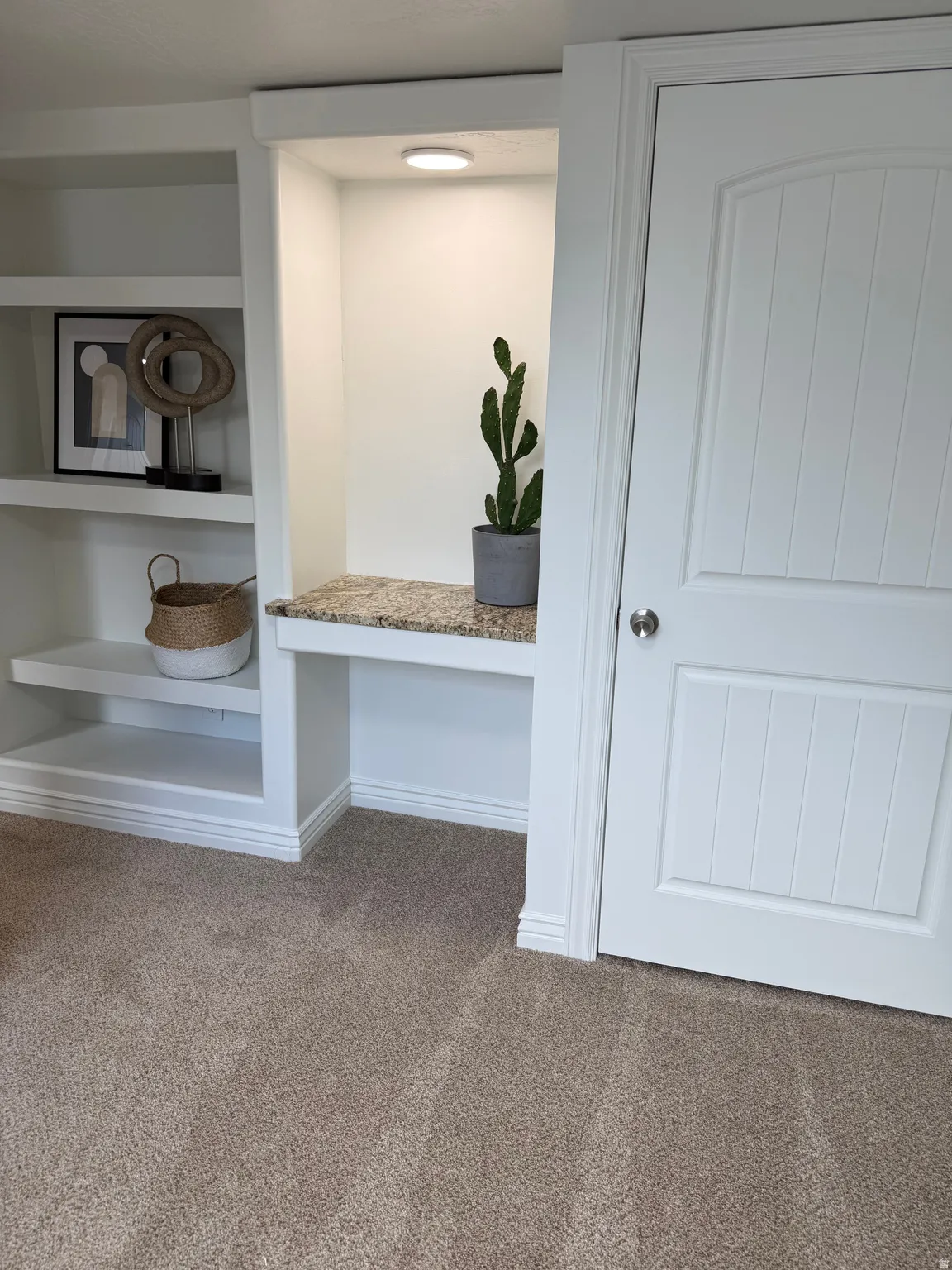Built-in shelving with recessed lighting, integrated desk surface with granite, and paneled door