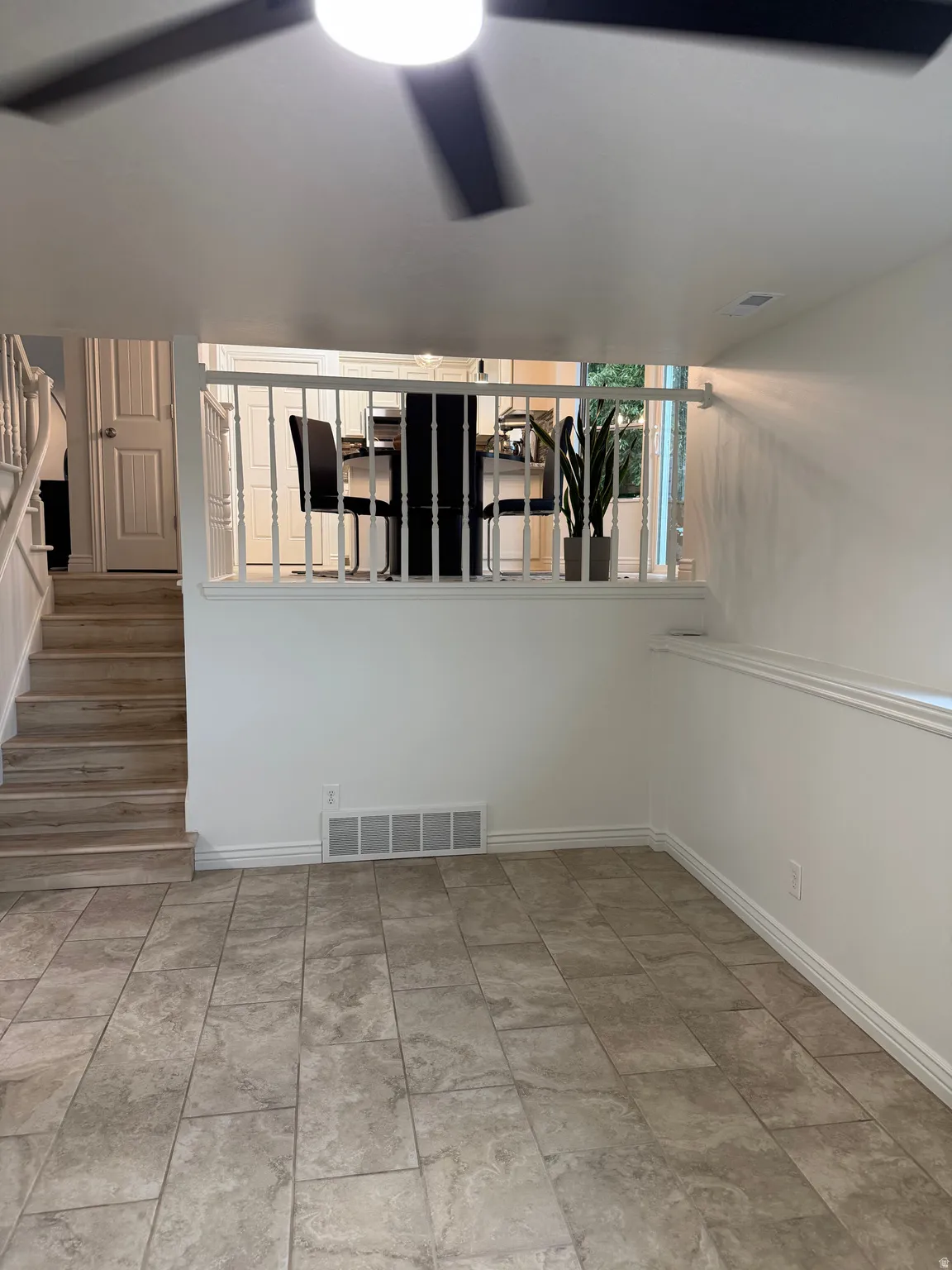 Tiled flooring with white baseboards, wood-finish stairs, and a partial balustrade
