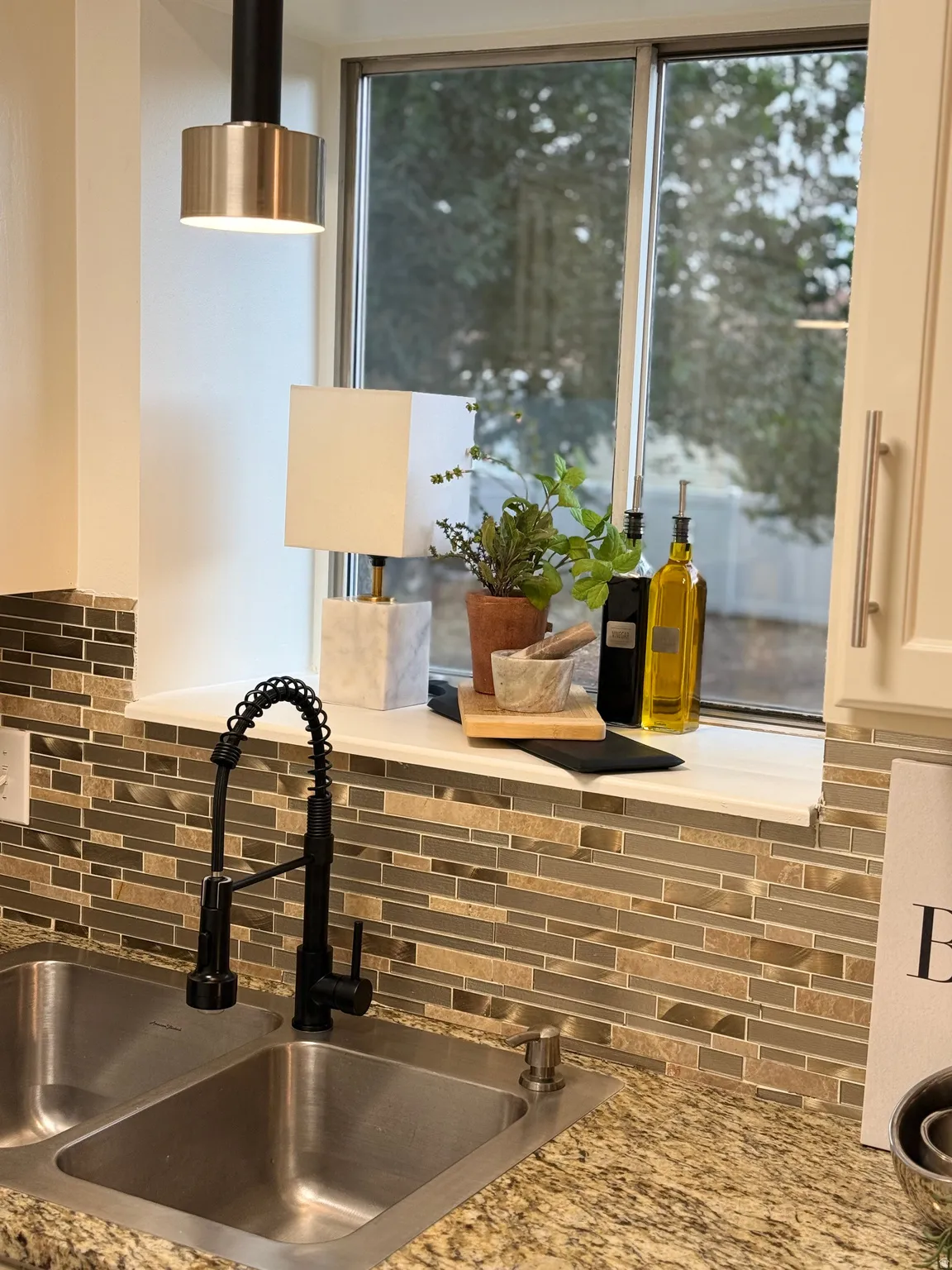 Double basin stainless steel sink with a matte black pull-down faucet, set into a speckled stone countertop