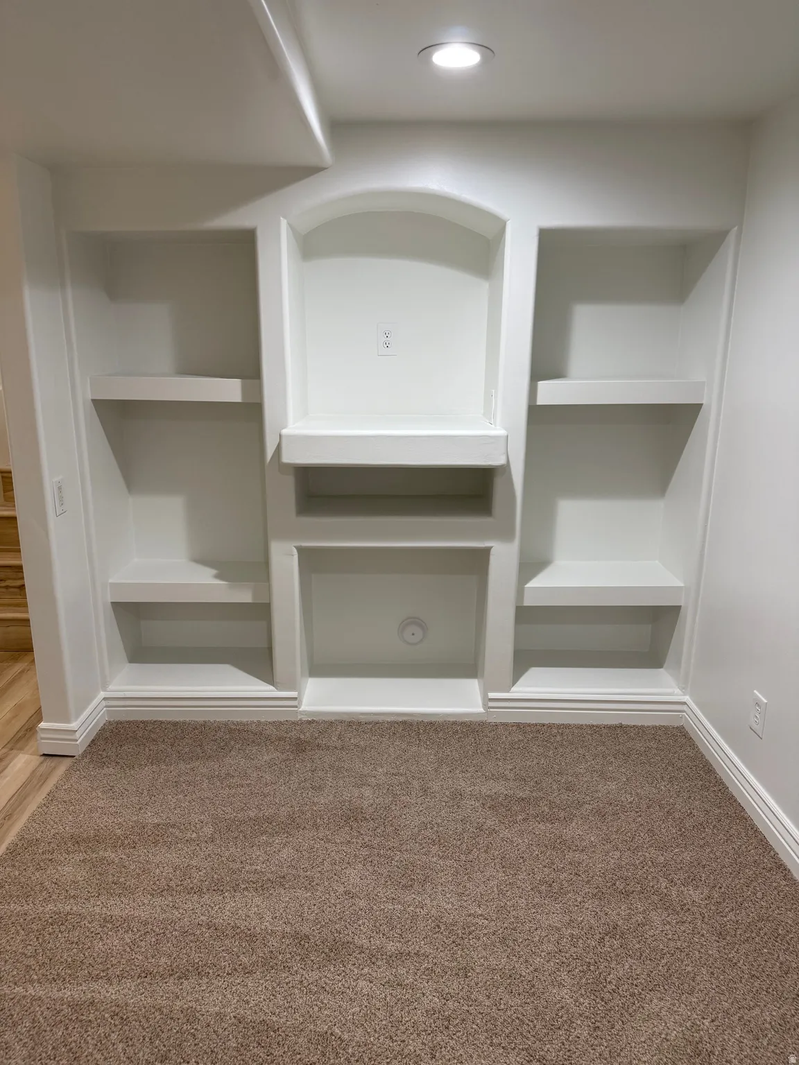 Built-in shelving unit featuring an arched niche, recessed lighting, and integrated outlets