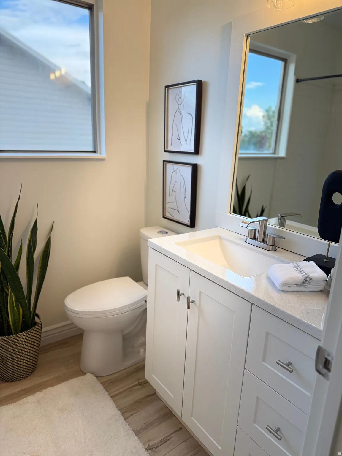 Modern 2nd upper level bathroom featuring a white vanity with integrated sink, quartz-finish countertop, and LVP flooring