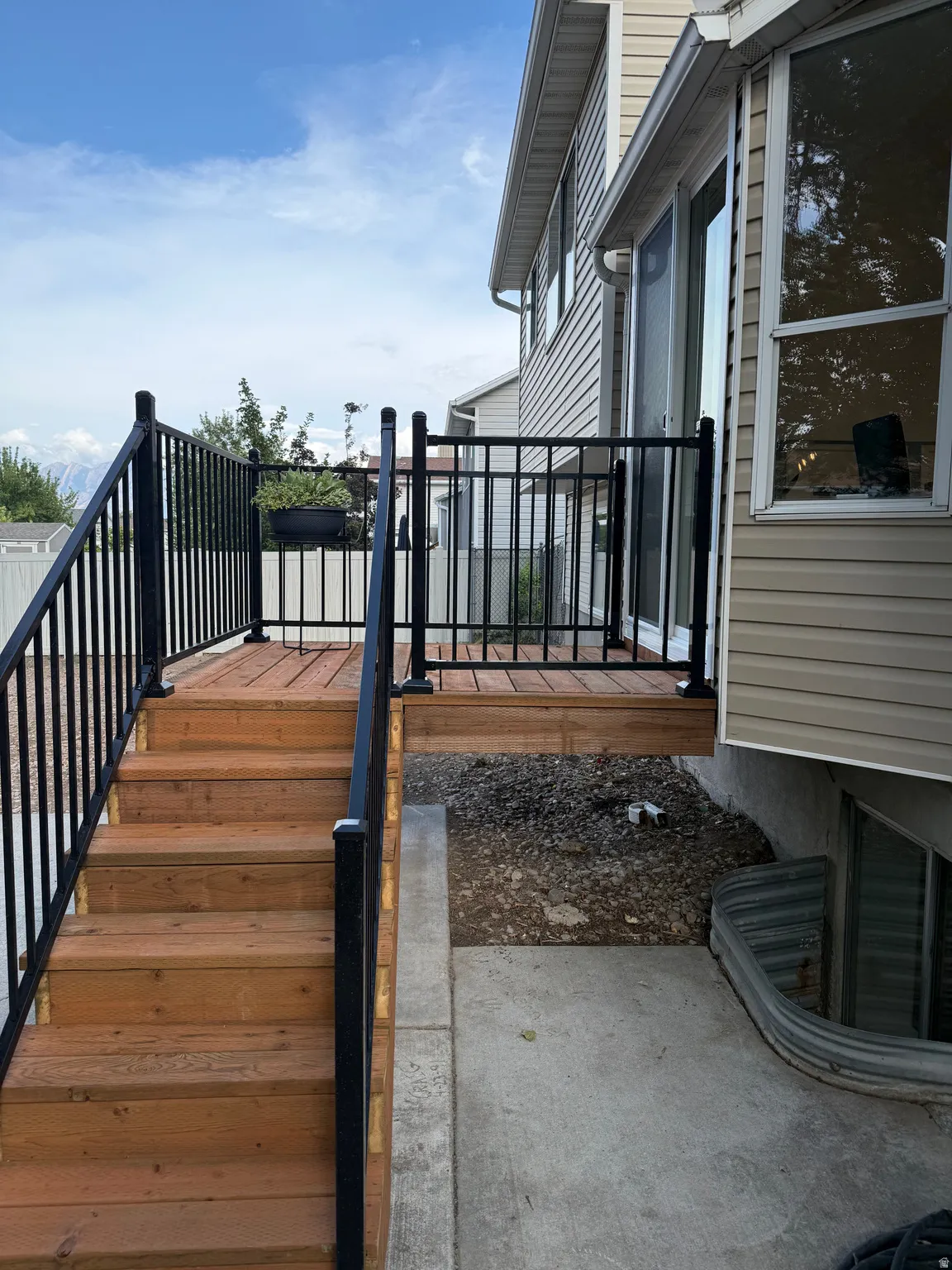 Exterior deck featuring wood-finish decking, black metal railings, and wood-finish stairs