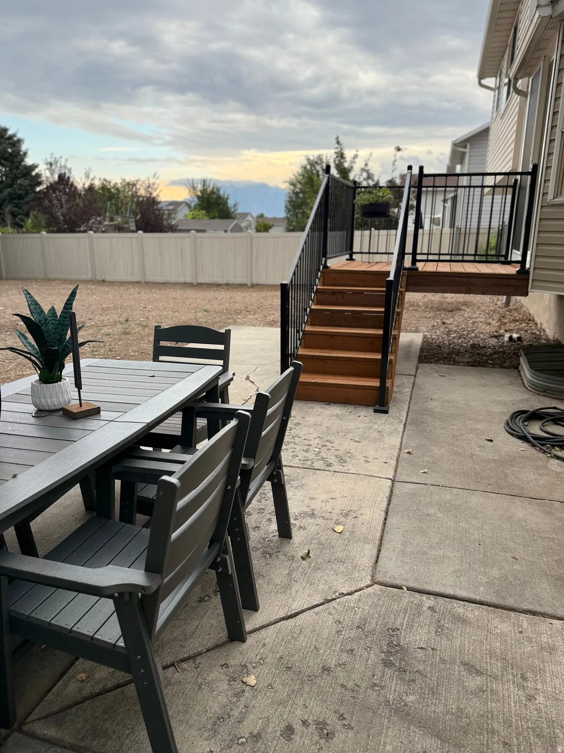 Expansive concrete patio with direct access to a multi-level wooden deck featuring black metal railings