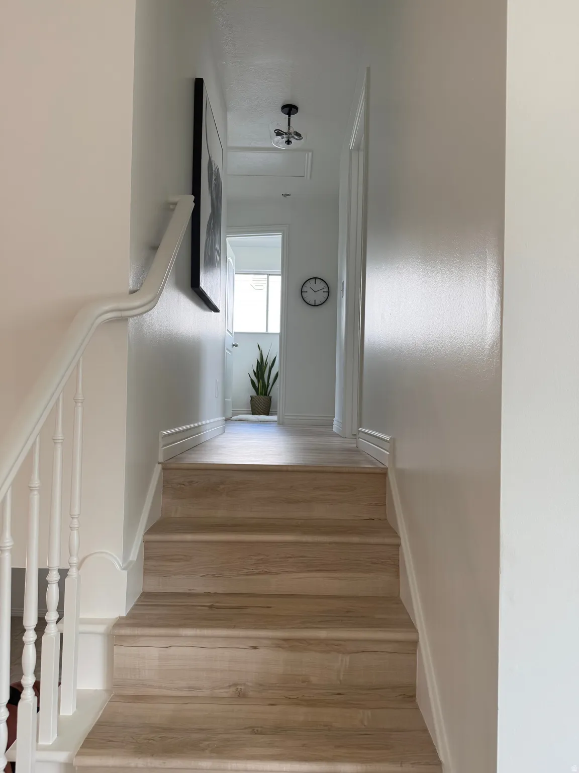 Staircase with wood-finish treads and risers, white balusters, and a matching handrail