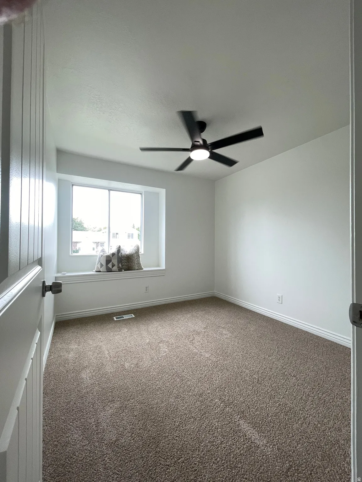 Recessed window seat with a white trim, ceiling fan with integrated lighting, and neutral tone carpet
