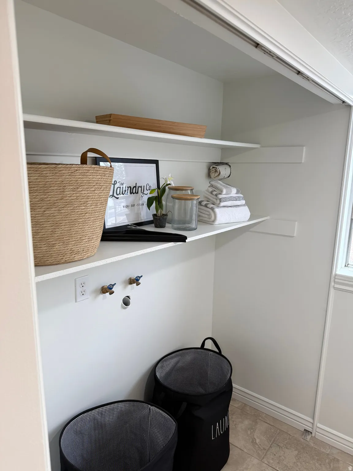 Laundry area with tile flooring, built-in shelving, white walls, and utility hookups