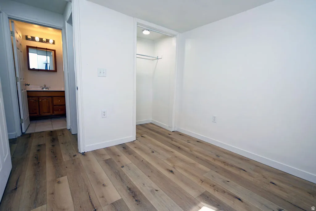Wood-finish flooring throughout, white painted walls, and an open closet with a built-in hanging rod