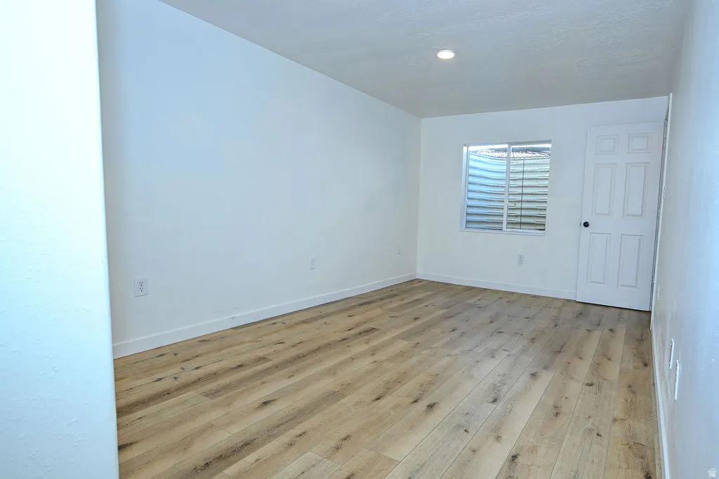 Wood-finish flooring with white walls, a white paneled door, and a recessed ceiling light