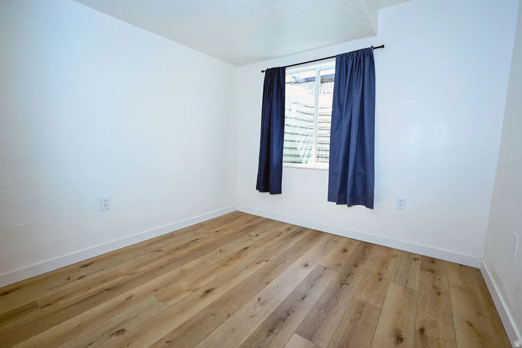 Neutral wall color with wood-finish flooring and a single window
