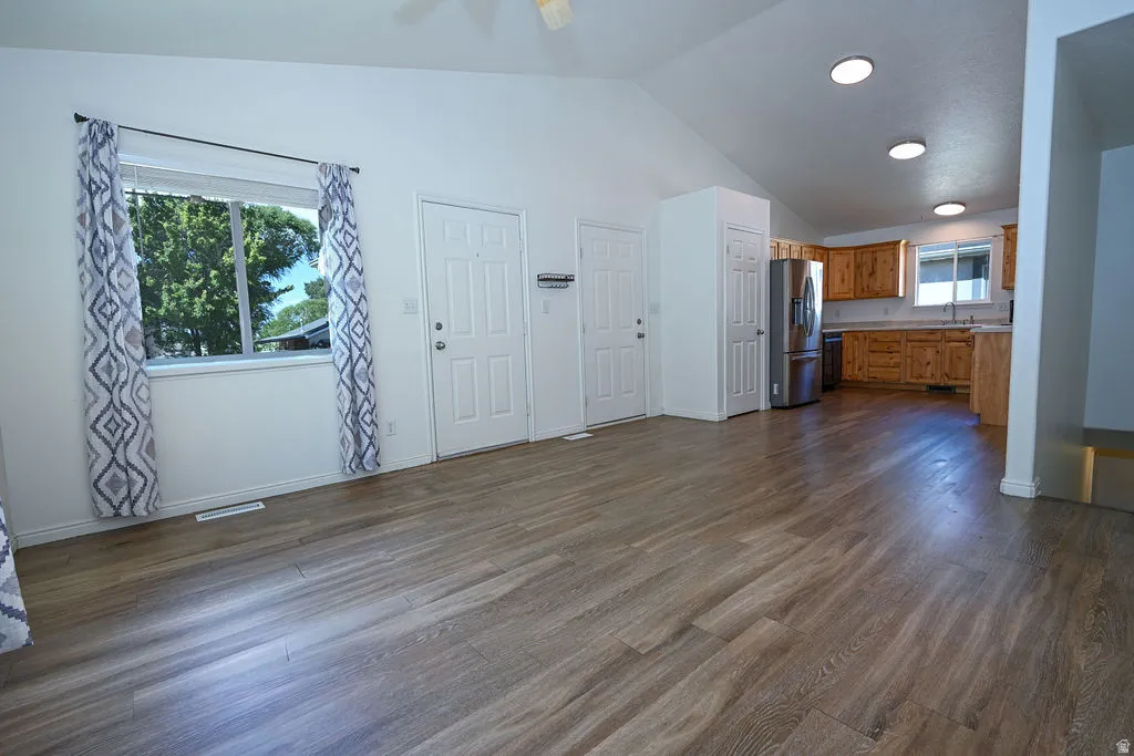 Vaulted ceilings, wood-finish flooring, recessed lighting, wood cabinetry, and stainless steel appliances
