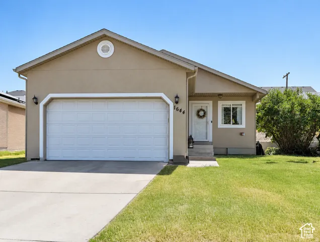 Single-story residence featuring a tan stucco exterior, concrete driveway, attached one-car garage, and white-trim accents