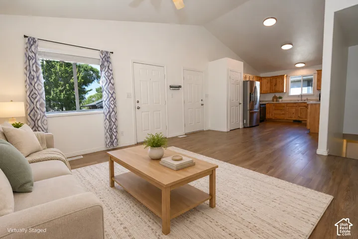 Vaulted ceilings, wood-finish flooring, recessed lighting, and kitchen cabinetry with integrated stainless steel appliances