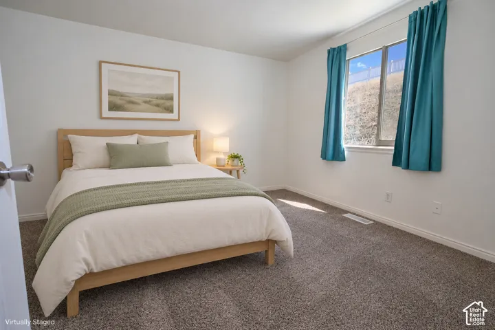 Bedroom featuring neutral-toned carpeting, crisp white wall finishes, and a single-pane window