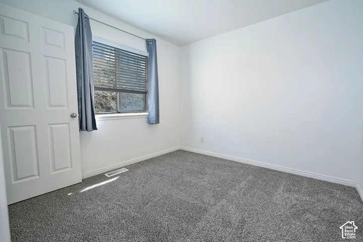 Gray carpet flooring, white walls, and a window with horizontal blinds