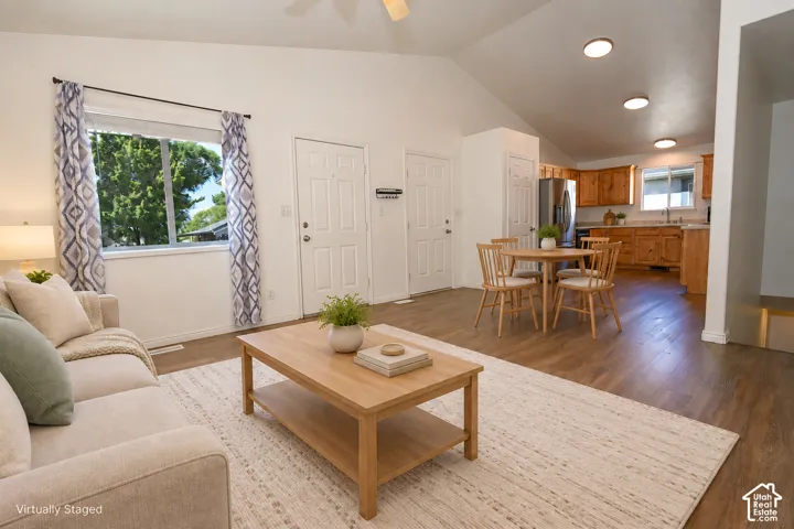 Open-concept floor plan featuring vaulted ceilings, wood-finish flooring, recessed lighting, and a kitchen with wood cabinetry