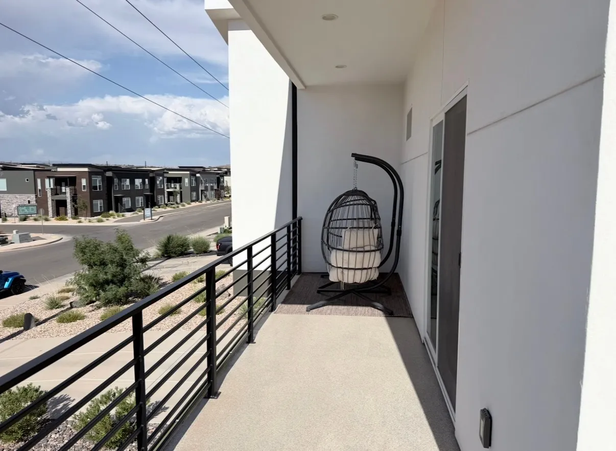 Private balcony with concrete flooring, modern black metal railings, and a sliding glass door