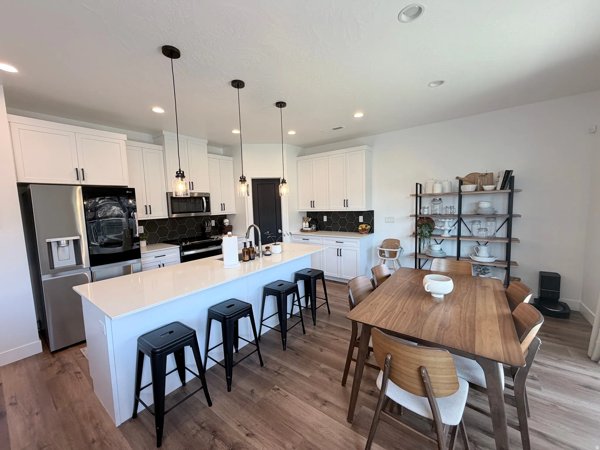 Kitchen island with white countertop, recessed lighting, wood-finish flooring, white cabinetry, and a black hexagonal tile backsplash