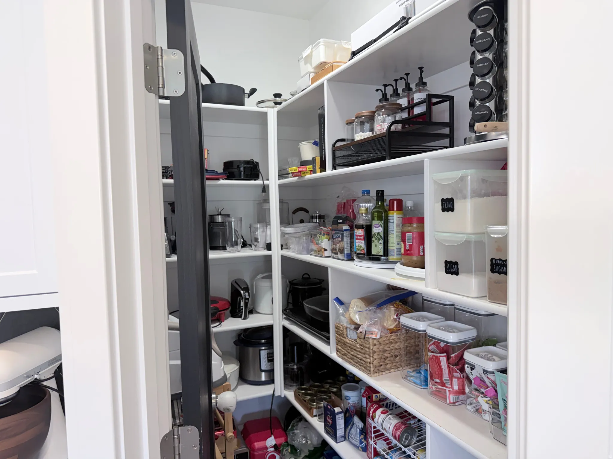 Walk-in pantry with extensive white shelving and a dark-paneled door