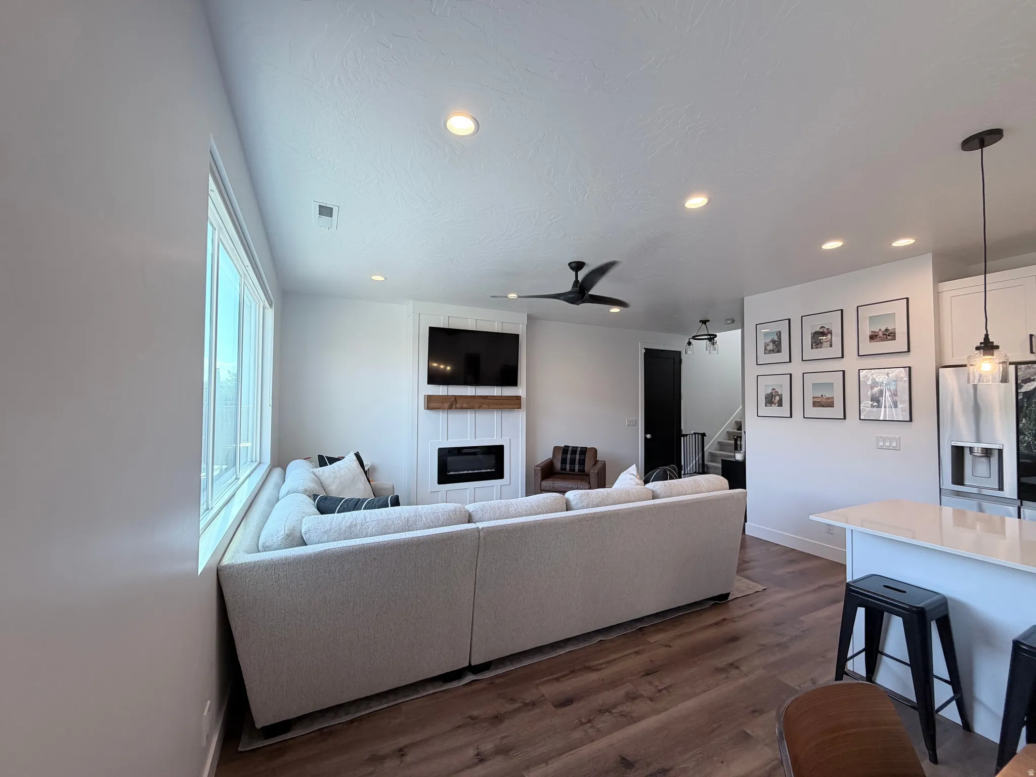 Recessed lighting, wood-finish flooring, large windows, ceiling fan, and a built-in fireplace feature