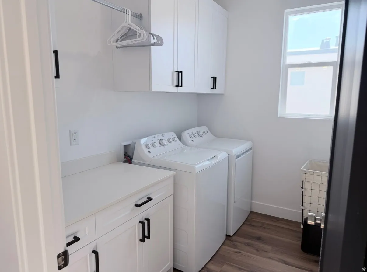 White cabinetry with black hardware, white countertop, wood-finish flooring, and a window